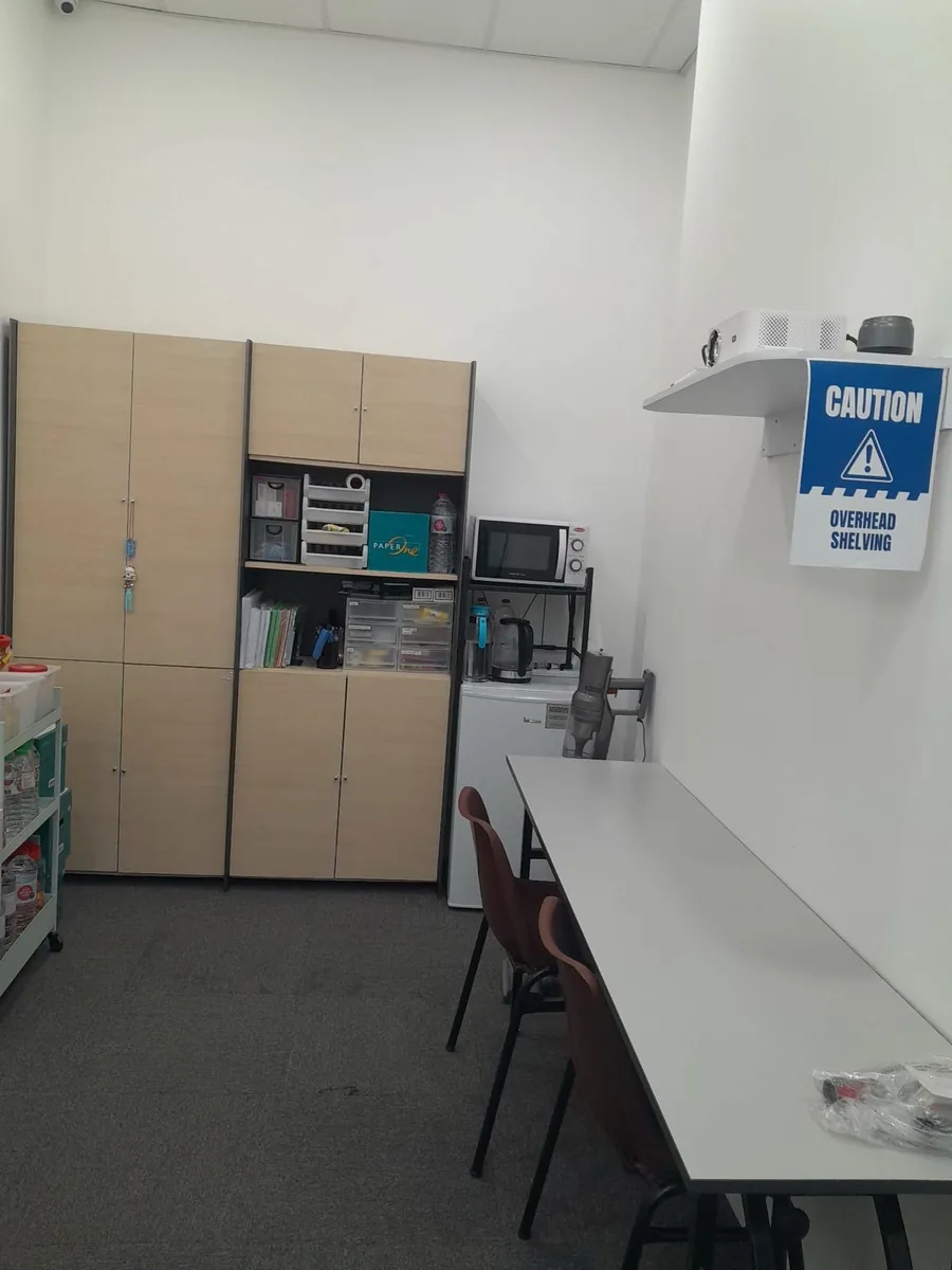 Office pantry area with wooden cabinets and appliances — after clean